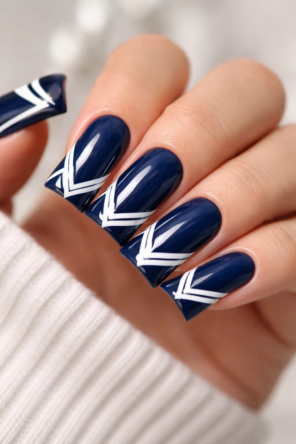 Navy blue duck nails with geometric white patterns on tips