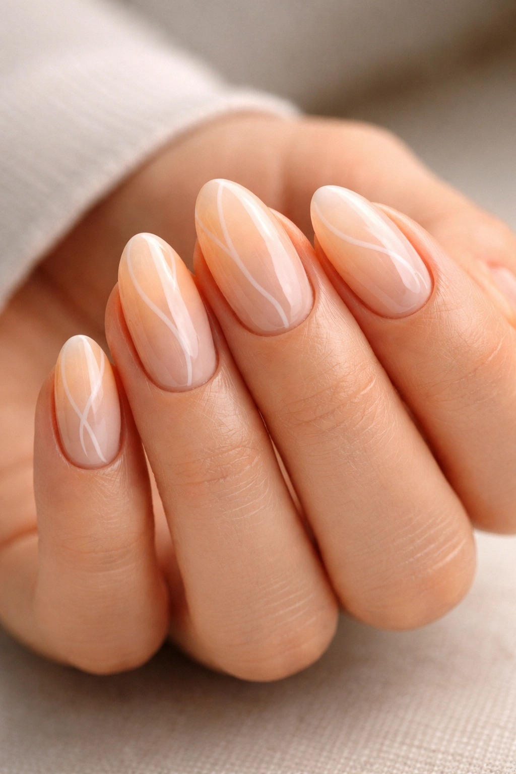 Hand with short almond nails showing a glossy, neat finish.