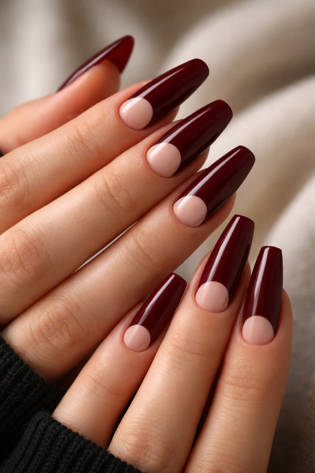 Nails feature a half-moon negative space with burgundy nails and glossy finish.