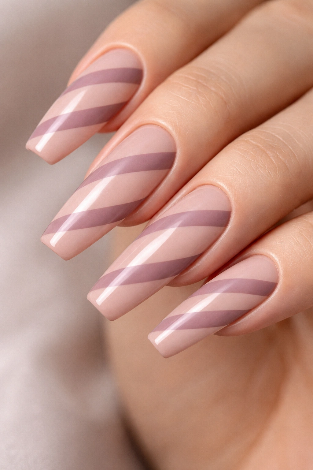 Close-up of long ballerina nails with negative-space diagonal ribbons in dusty mauve