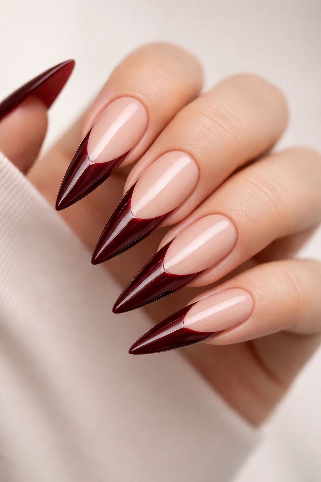 Close-up of dark red stiletto nails with negative space at the tip