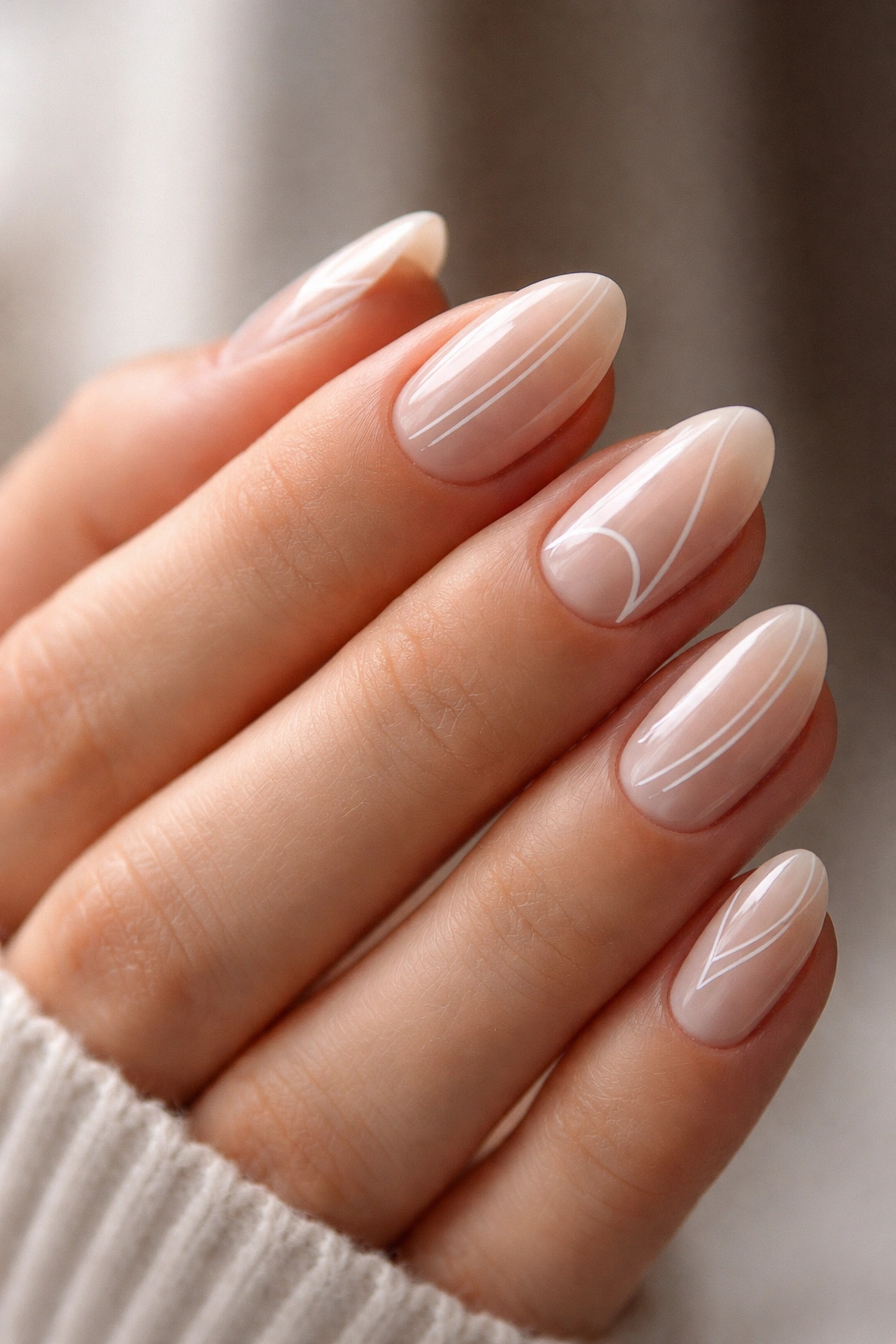 Close-up of short almond nails with negative space lines on a sheer nude base