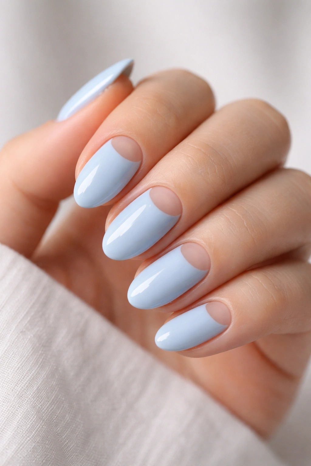 Close-up of light blue nails with negative-space half-moon at cuticle