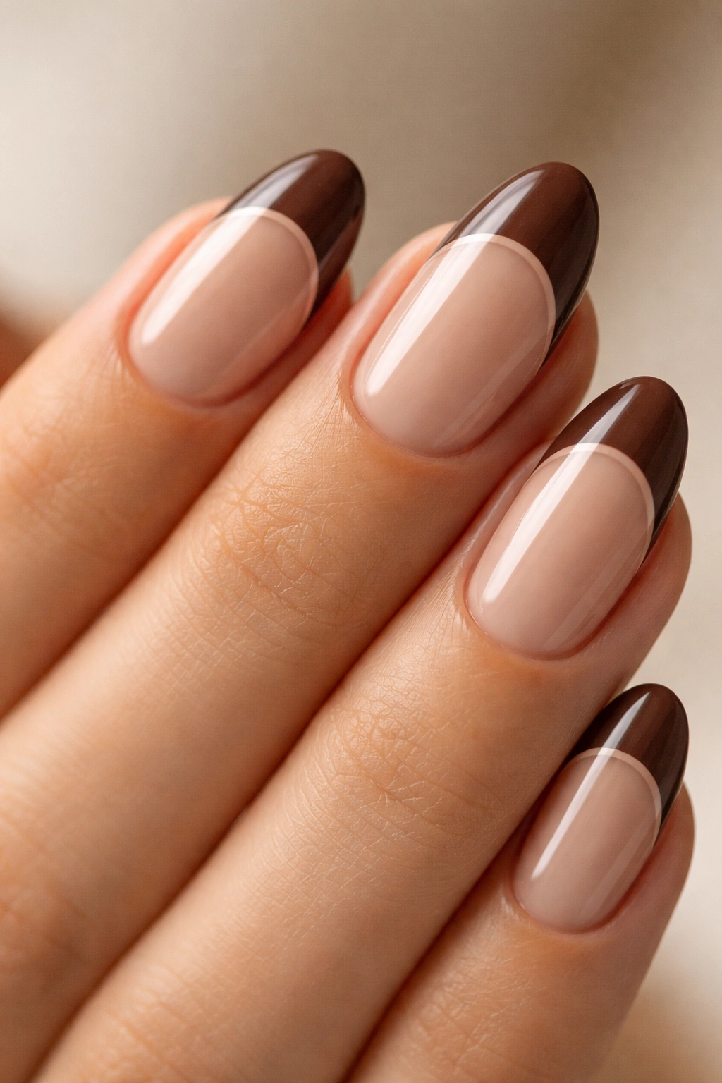 Close-up of short almond nails with negative-space brown tips and a clear central band.