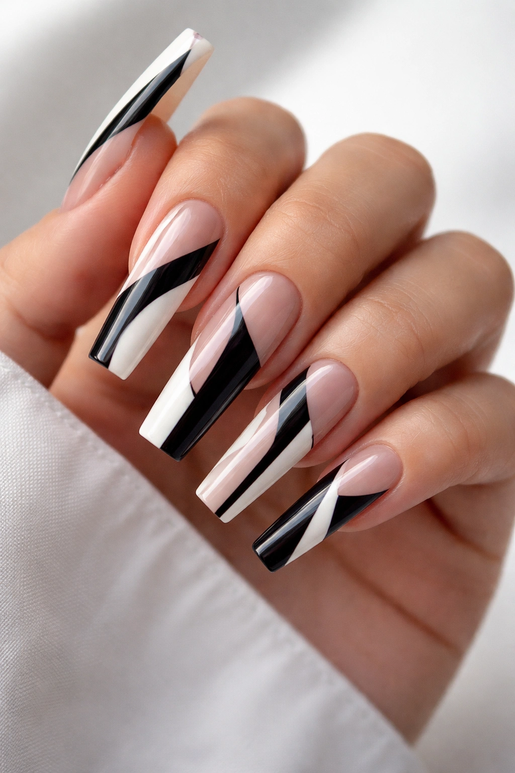 Close-up of coffin nails with negative-space stripes and geometric shapes.