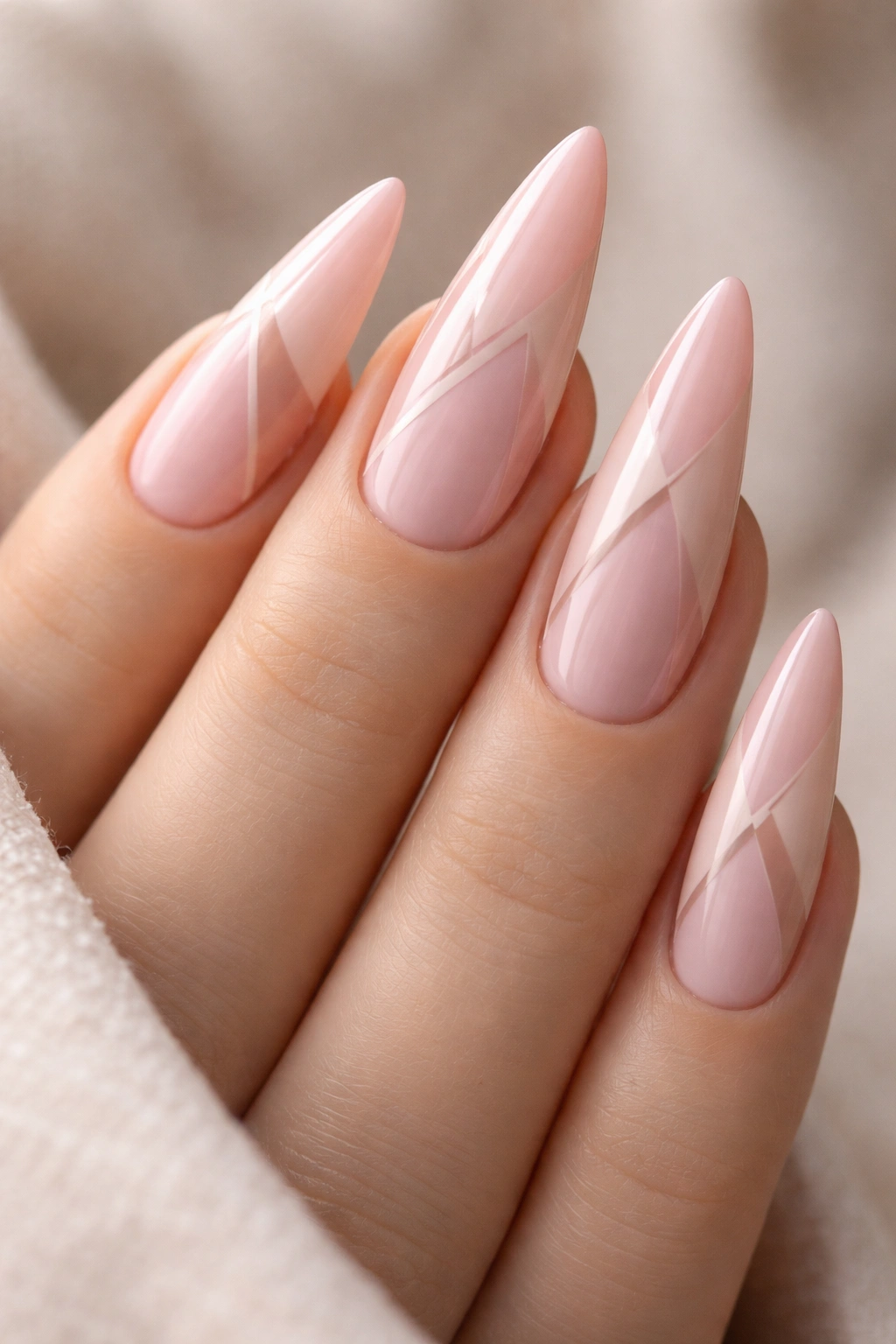 Close-up soft pink stiletto nails with nude negative space geometric design.