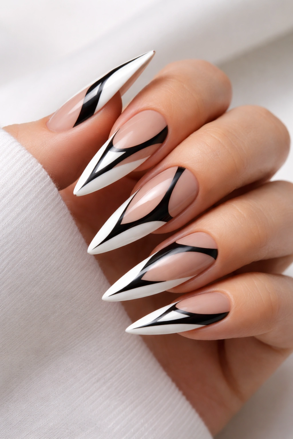Close-up of stiletto nails with black geometric cutouts on white base showing negative space