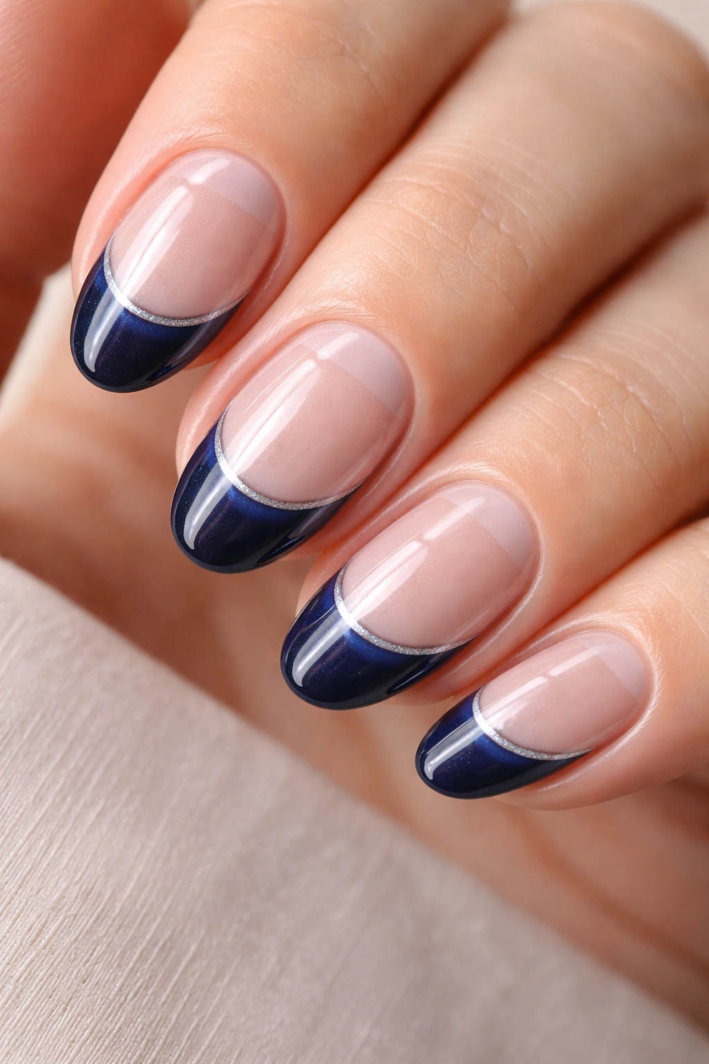 Close-up of a short almond nail with a transparent base and navy tip with a negative space window