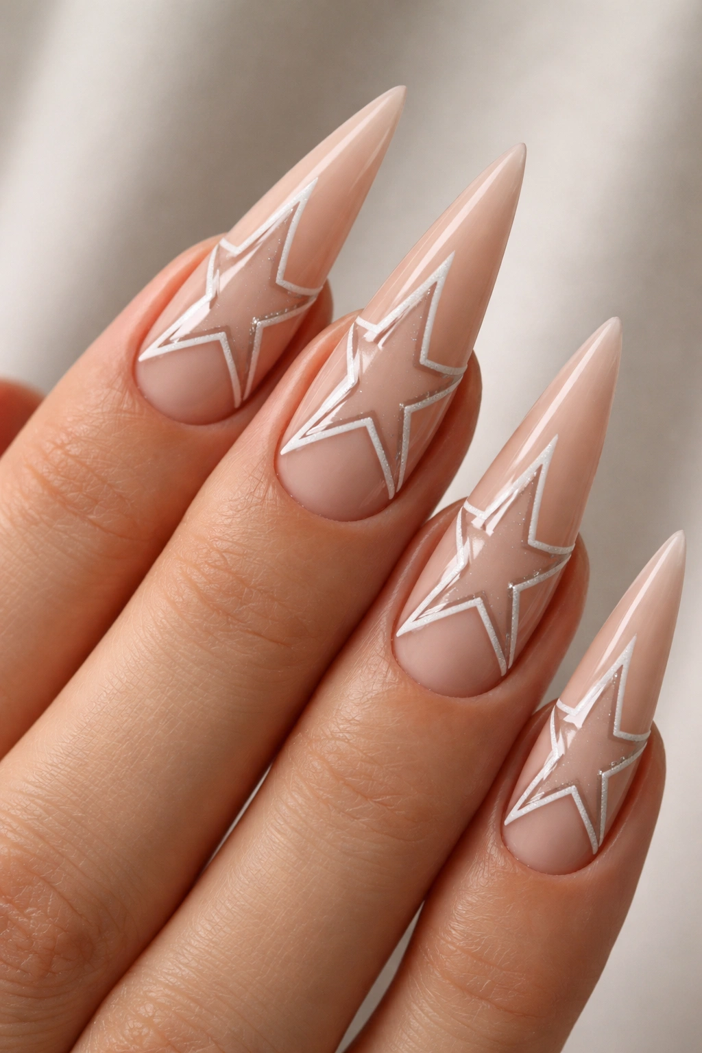 Nude stiletto nail showing negative-space star shapes with geometric blocks