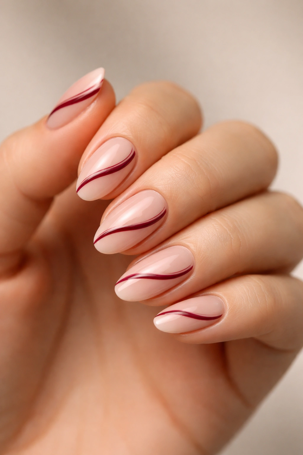 Close-up of short almond nails with nude base and diagonal swirl