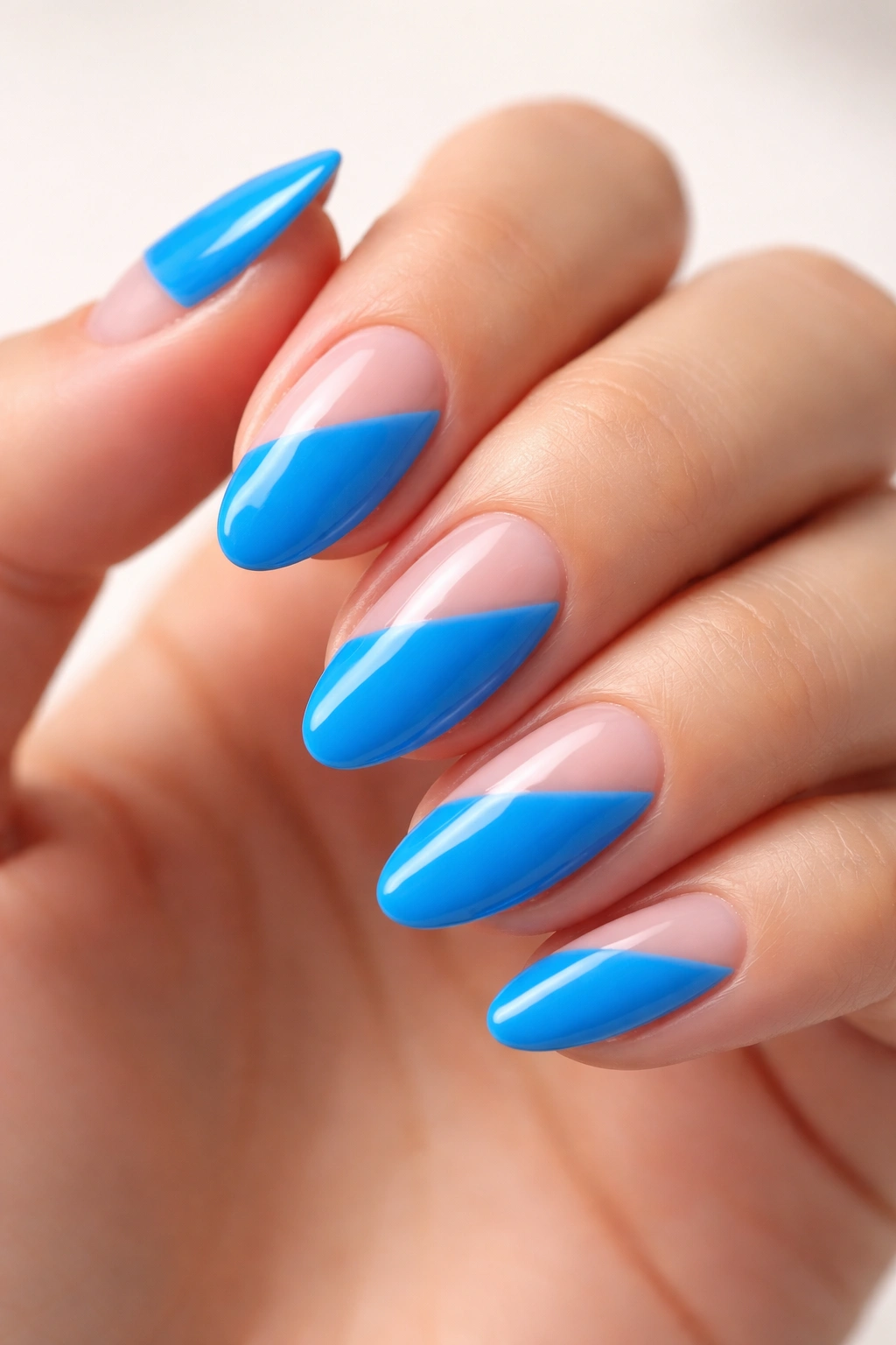 Close-up of a short almond nail in neon blue with a diagonal negative-space cutout