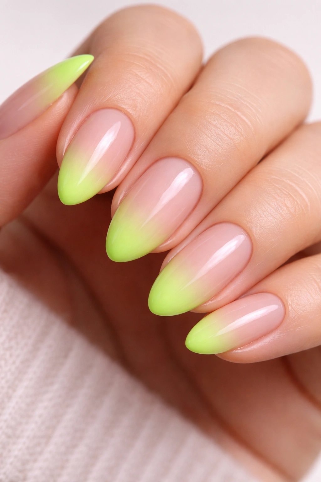 Close-up of short almond nails with neon green French fade