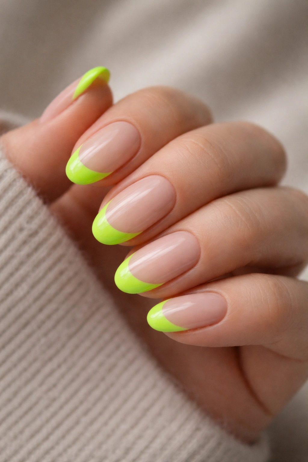 Close-up of short almond nails with neon green tips on nude base