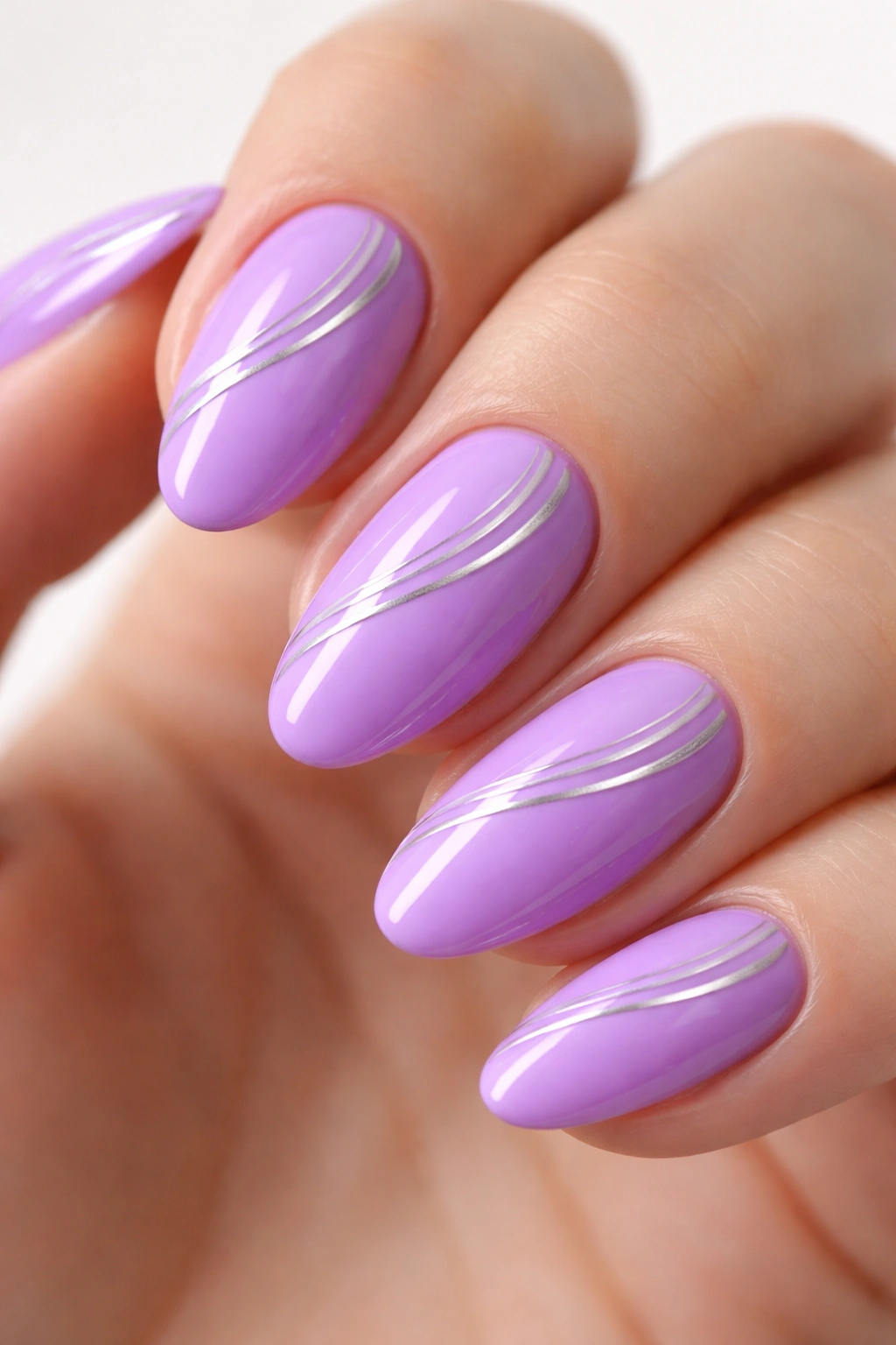 Close-up of a short almond lavender nail with delicate silver lines