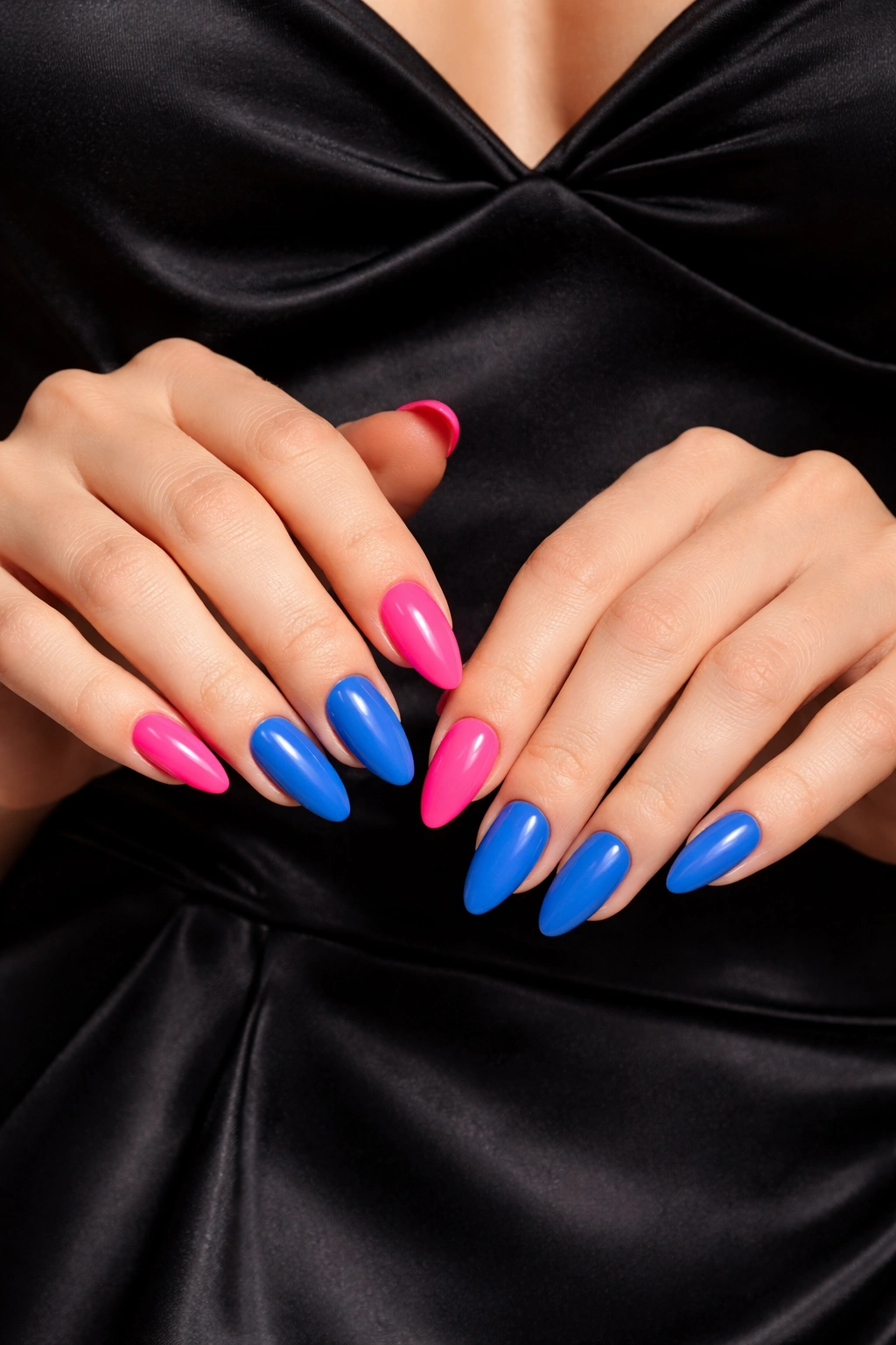 Close-up of neon pink and cobalt blue nails against black dress satin
