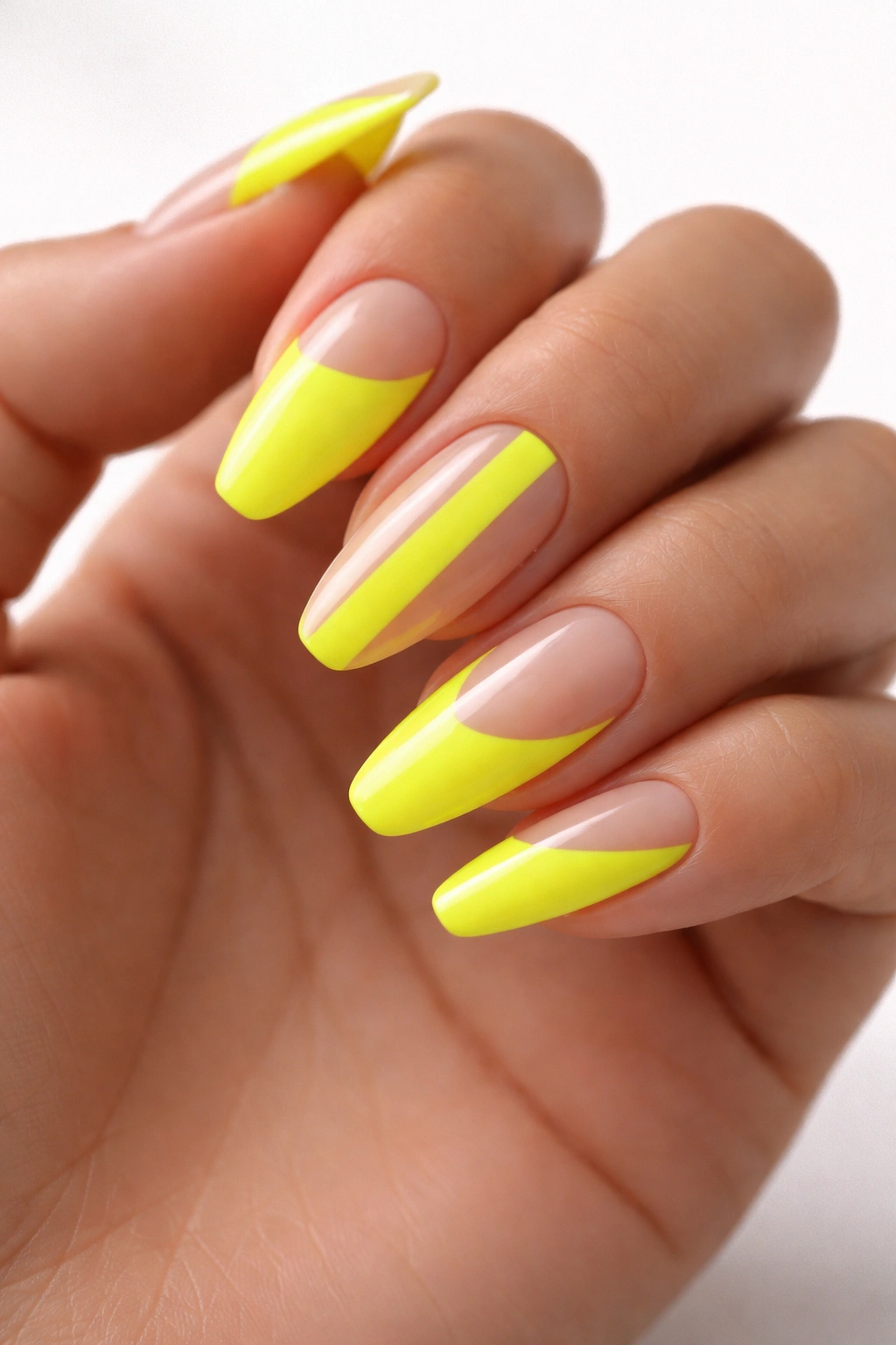 Close-up of neon yellow negative-space nails with half-moon and center-strip designs on a hand, studio lighting.