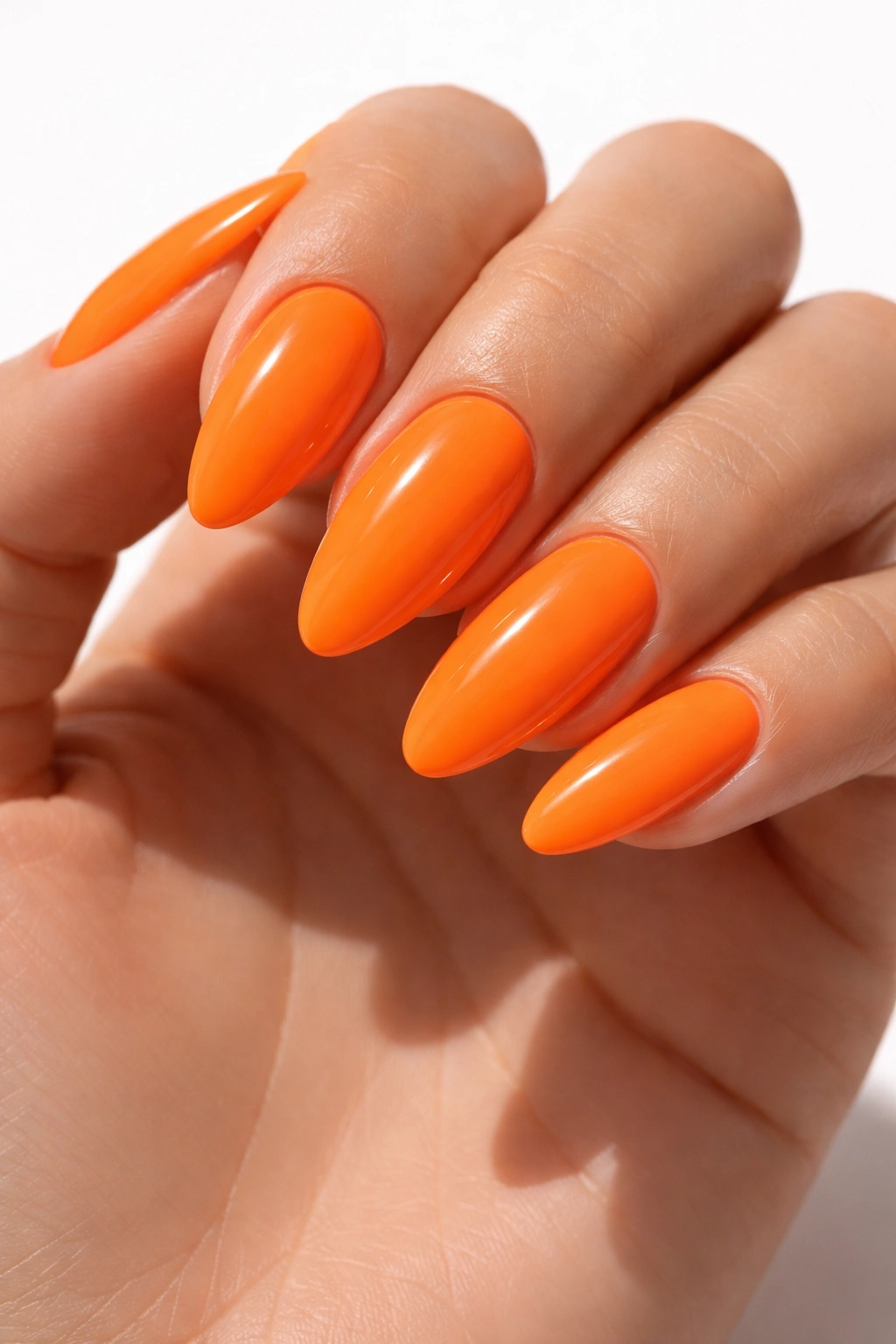 Close-up of neon orange almond nails with glossy finish on a bare hand