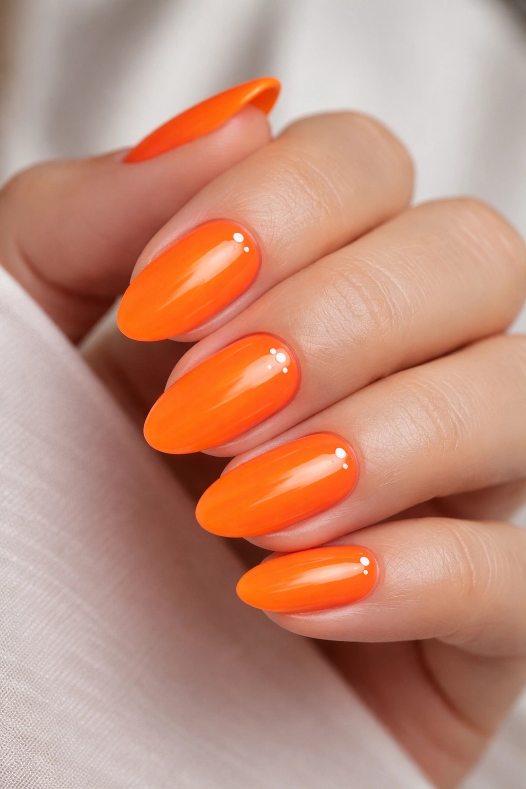 Close-up of neon orange nails with minimal nail art on short almond shapes