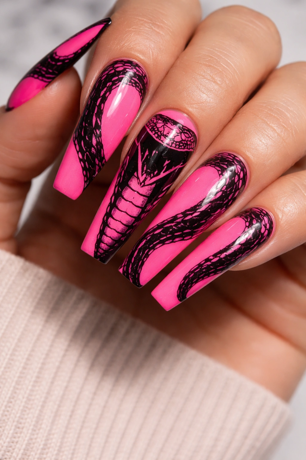Neon pink nails with black cobra pattern on coffin-shaped nails.