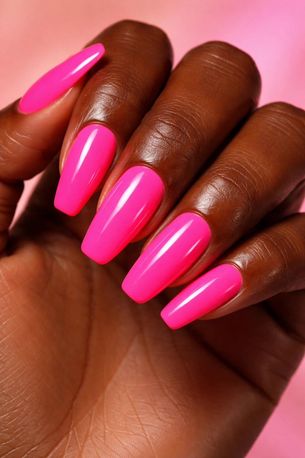 Close-up of dark-skinned hand showing glossy neon pink nails