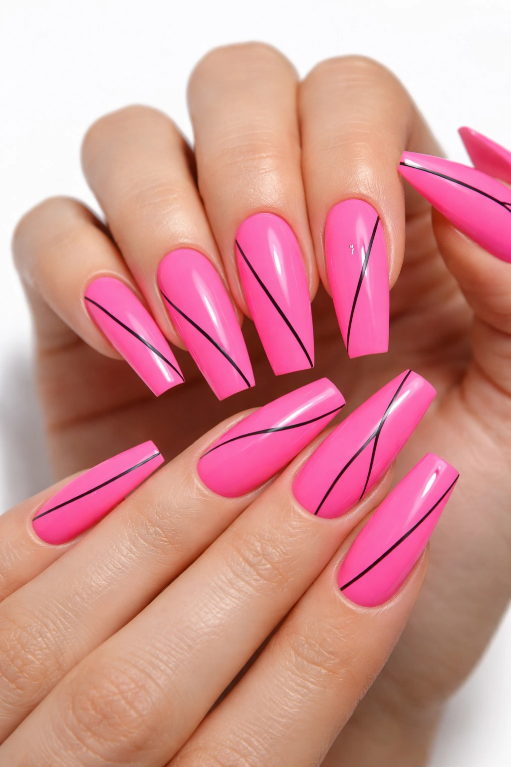 Close-up of neon pink coffin nails featuring a thin black line minimalist art on a white studio backdrop