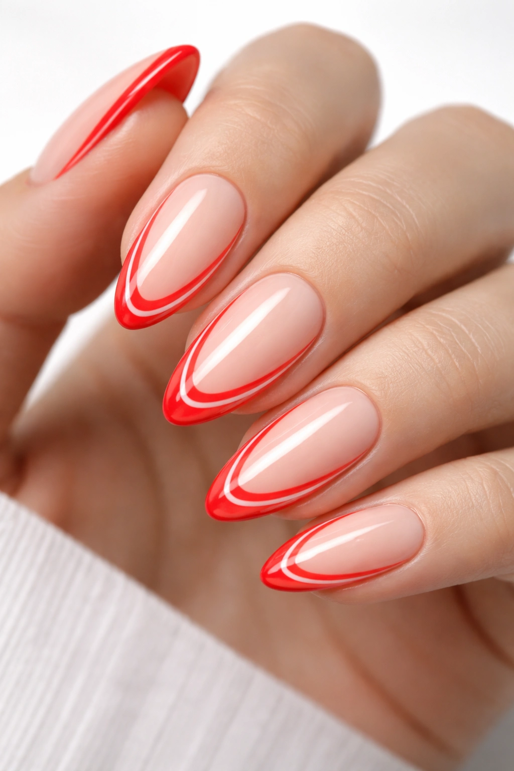 Close-up of almond nails with nude base and neon red negative-space tips