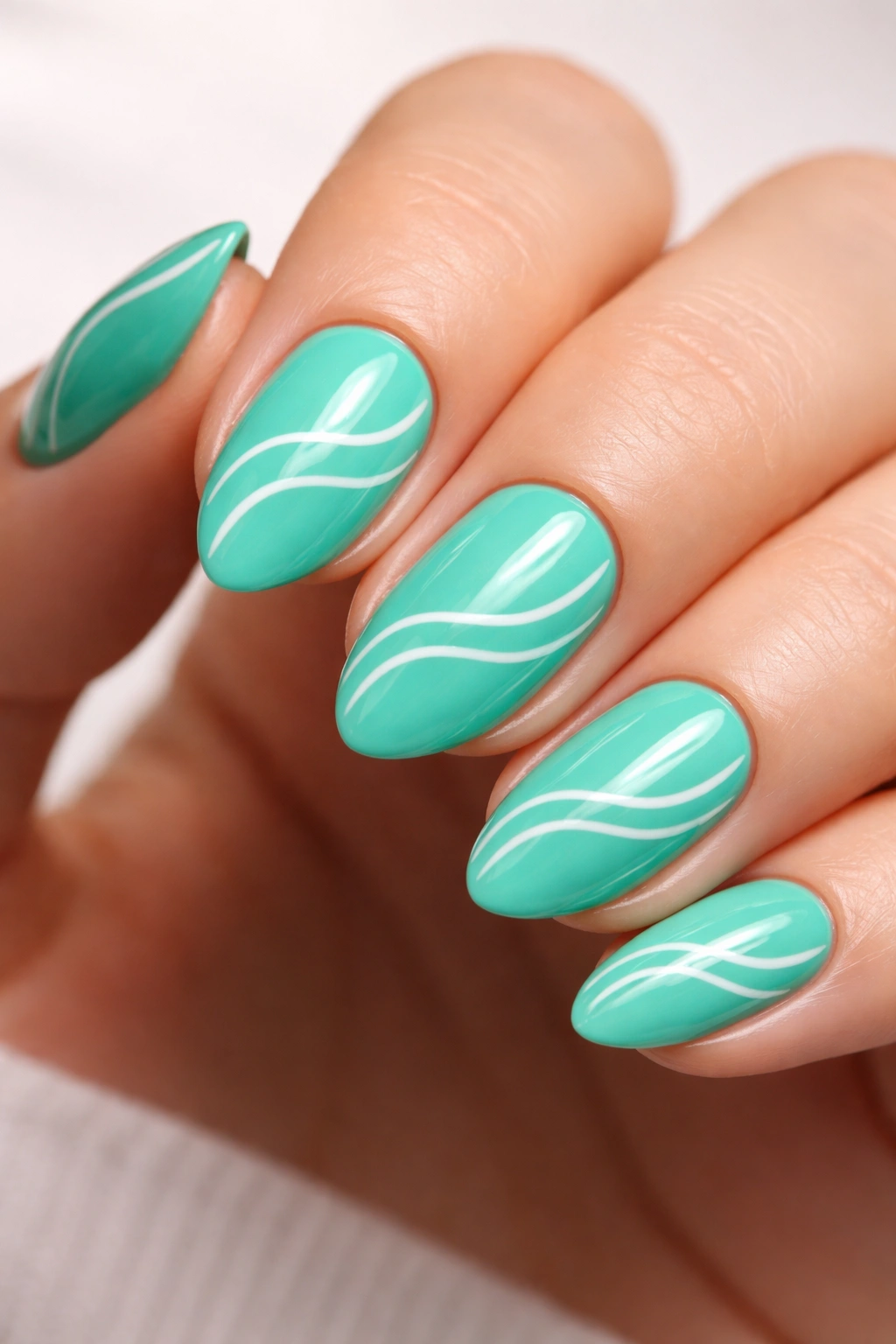 Close-up of a short almond neon teal nail with tiny white wave lines