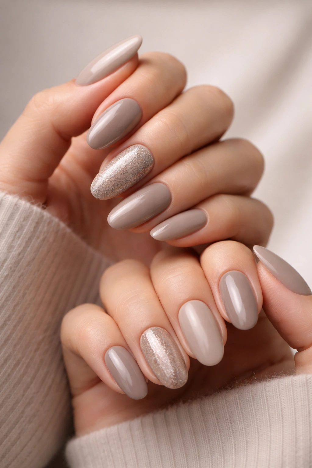 Two hands with neutral coordinated nails in greige and taupe
