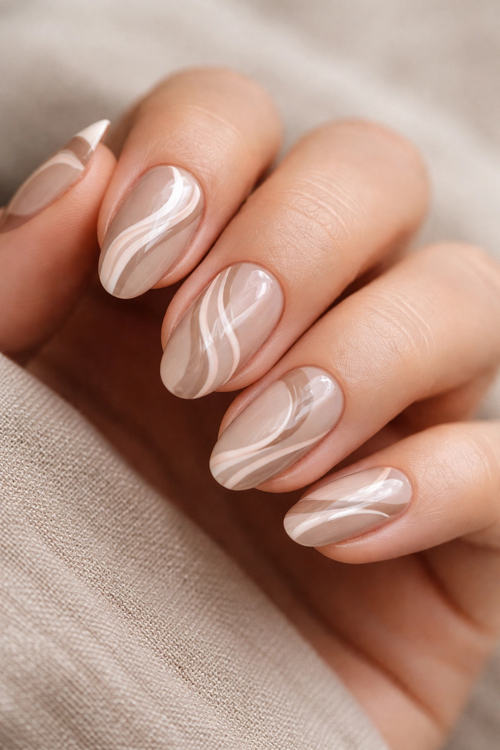 Close-up of short almond nails with beige taupe neutral swirls and negative space
