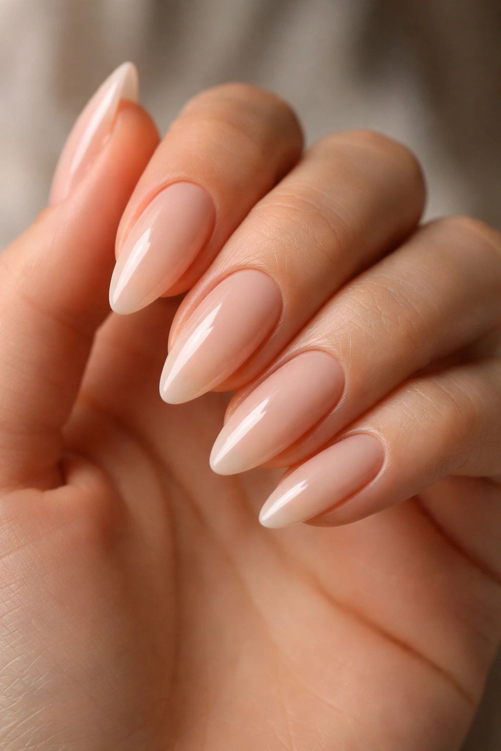 Close-up of nude almond nails matched to undertone with glossy finish