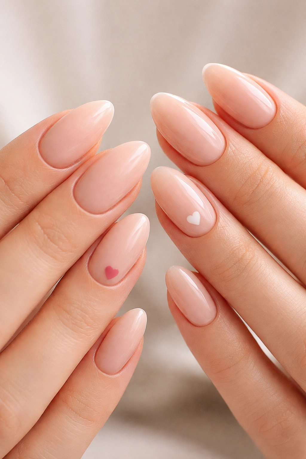 Nude almond nails with small hearts on ring fingers on both hands