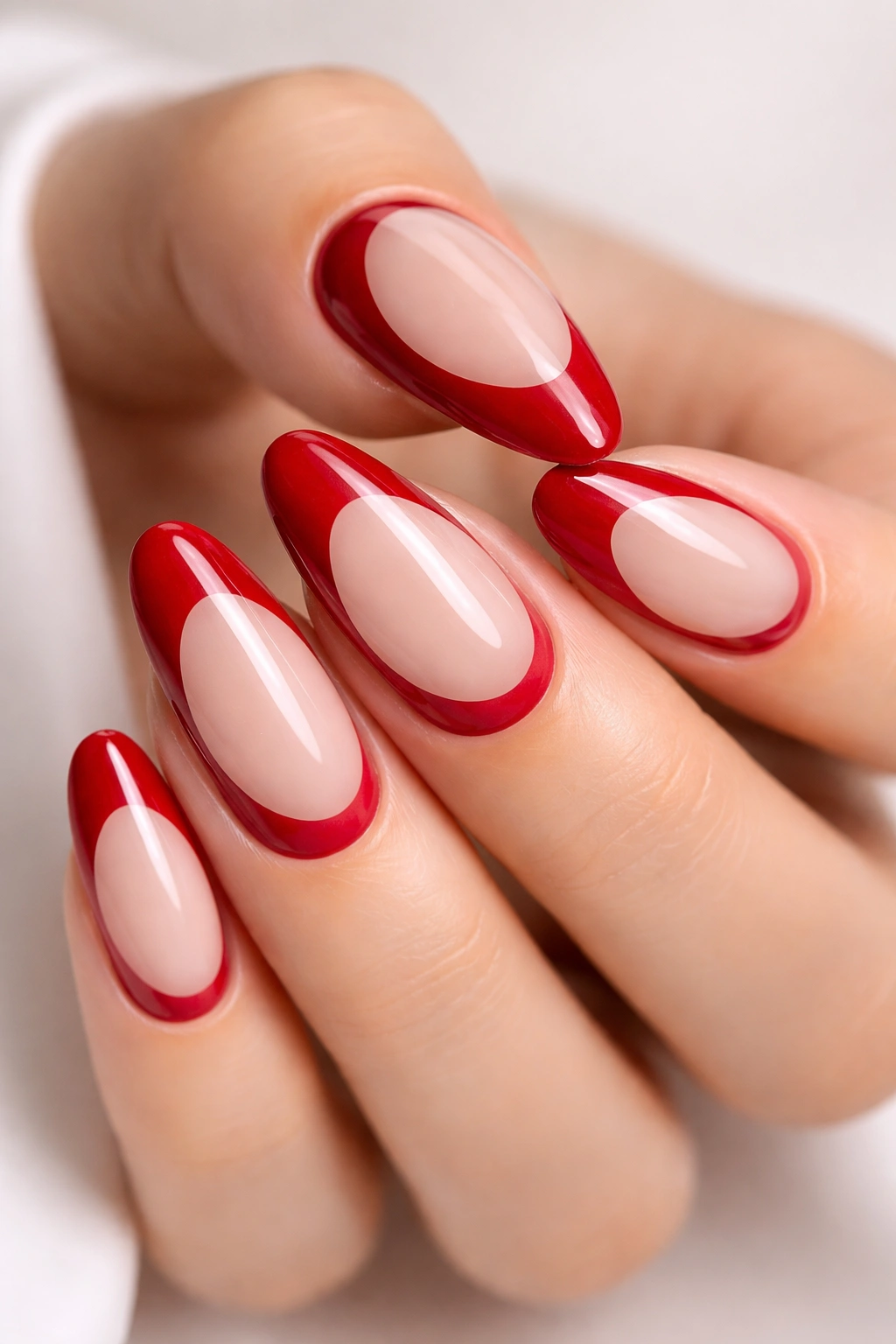 Close-up of nude-based nails with cherry red reverse design on long round nails