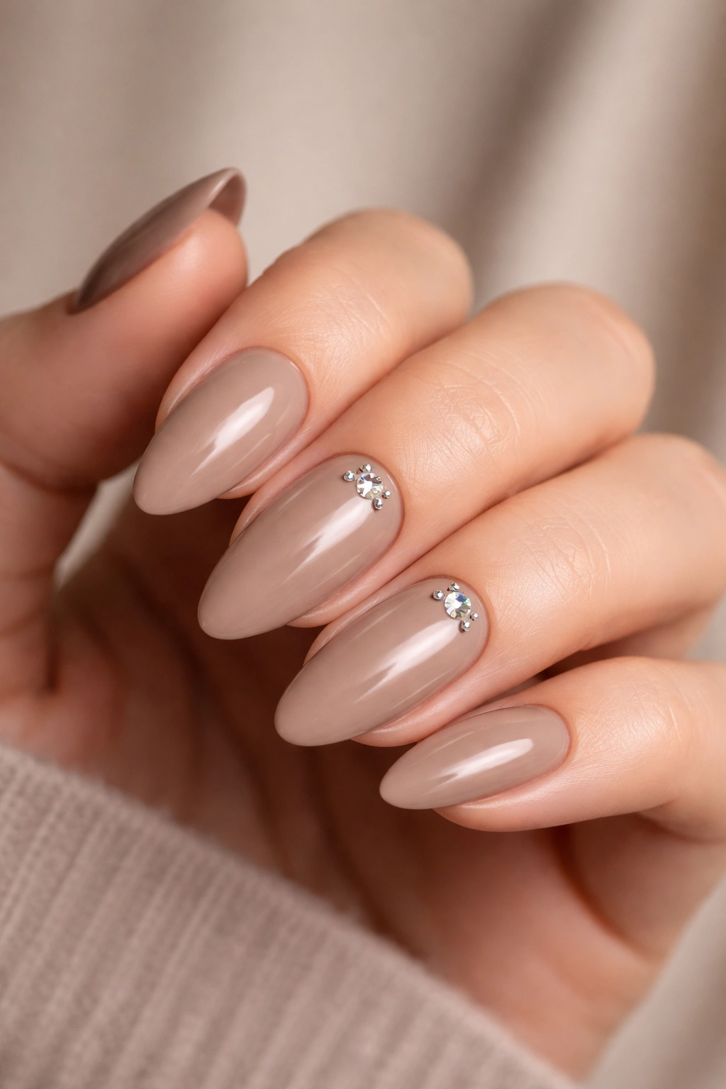 Close-up of nude brown nails with rhinestones near the cuticle