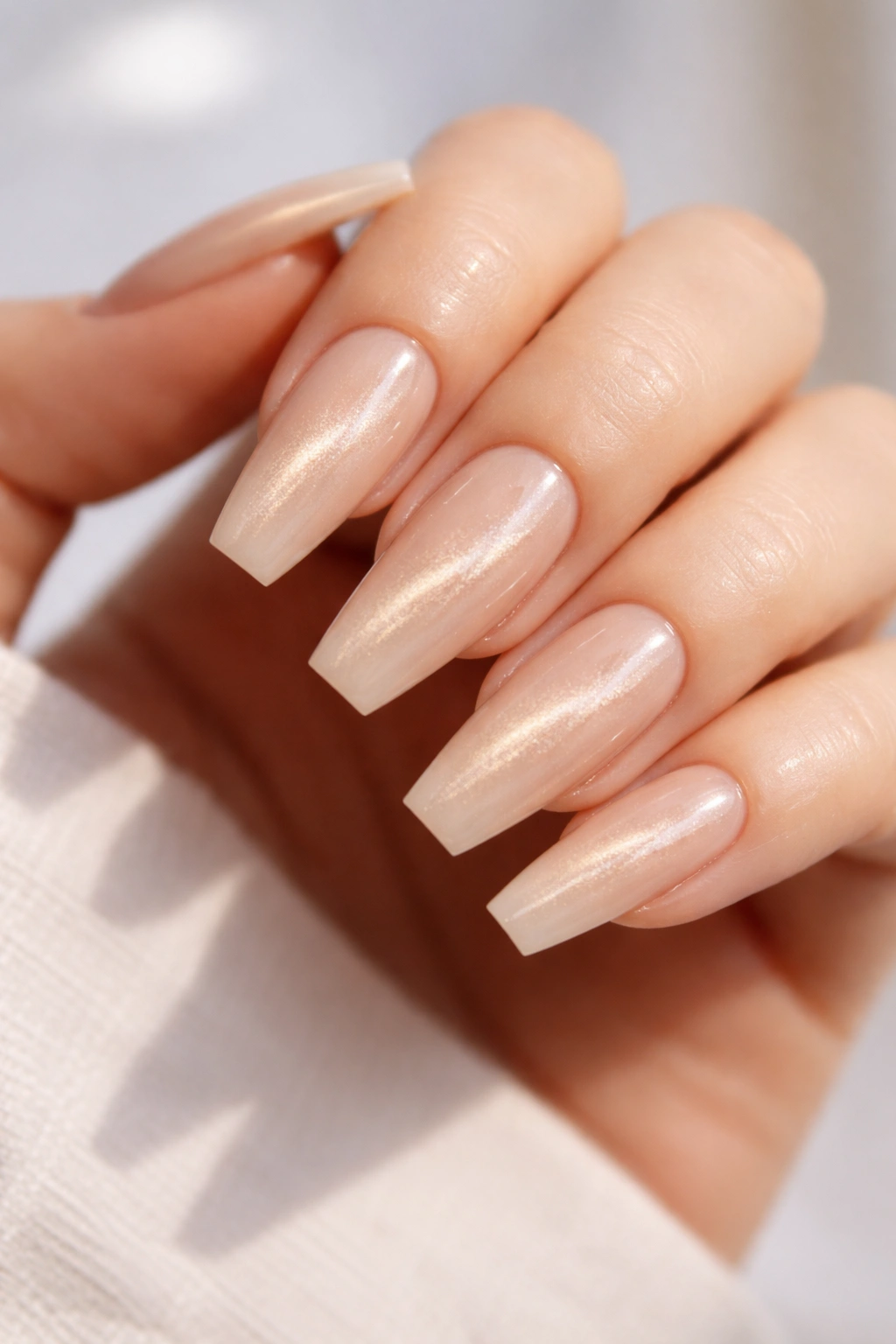 Nude cat eye nails with champagne beam on a neutral background