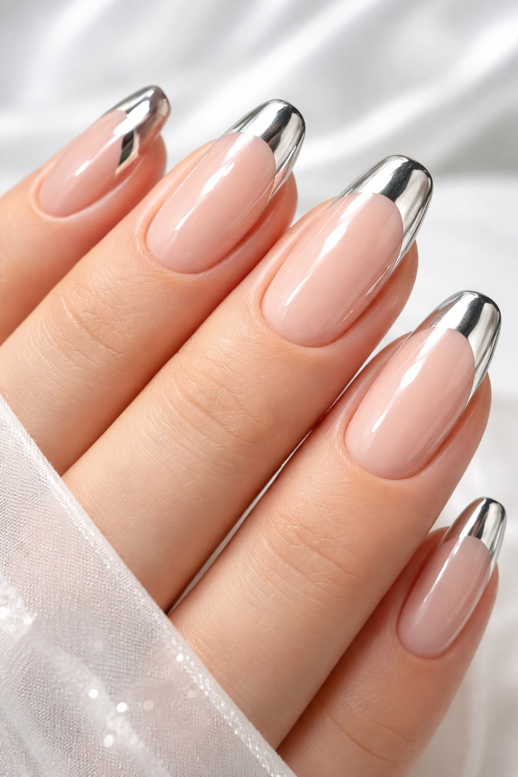 Close-up of nude chrome nails with chrome tips on a clean background.