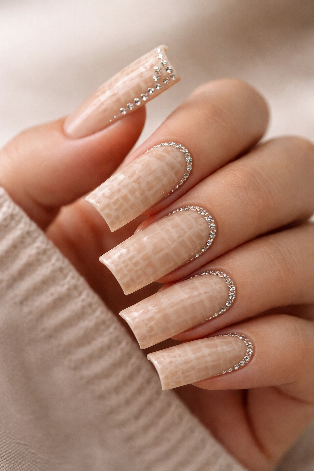 Close-up of nude duck nails with subtle croc texture and small rhinestones