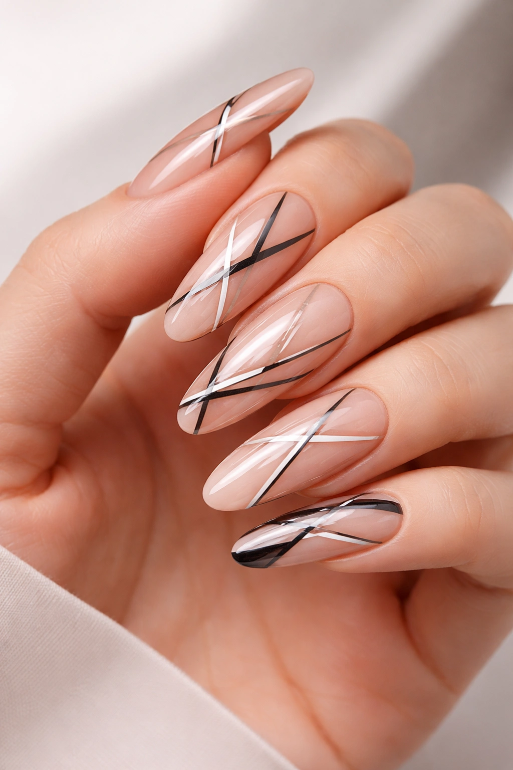 Close-up of glossy nude nails with geometric line art