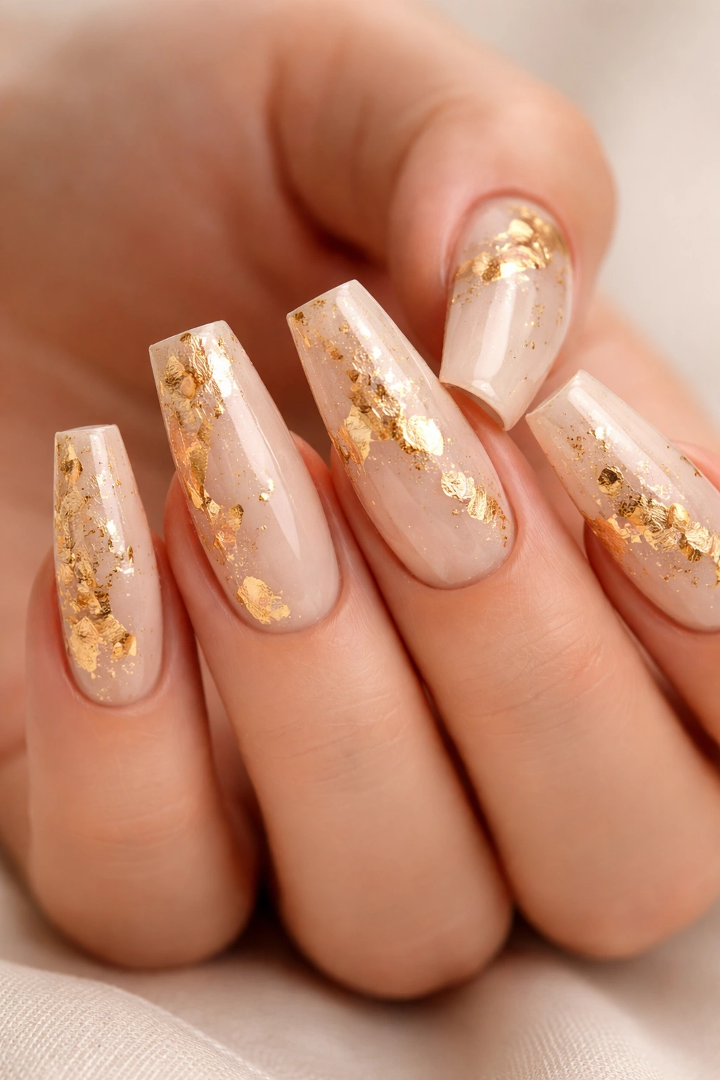 Close-up of nude coffin nails with gold foil accents