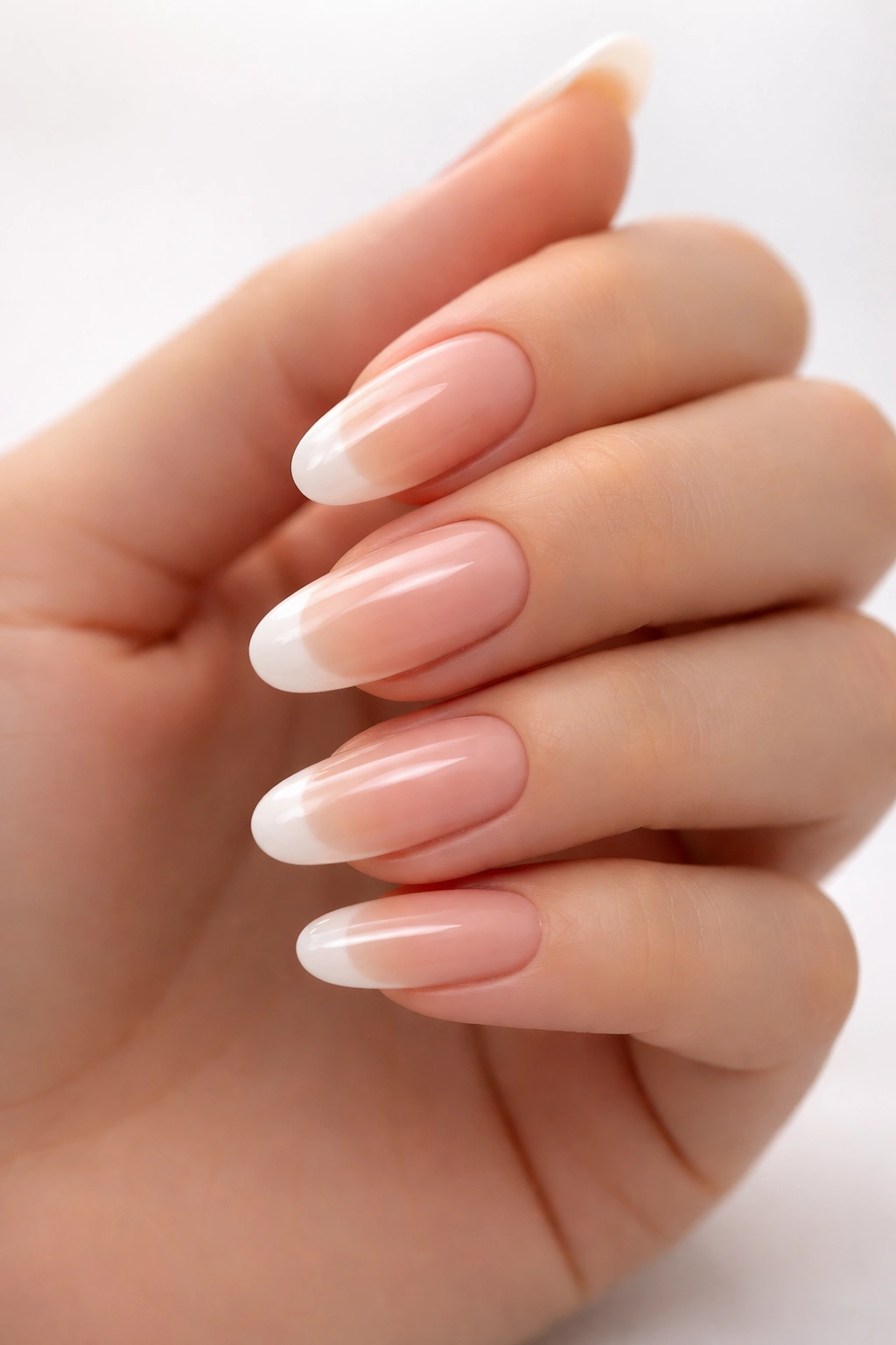 Close-up of long round nails with nude gradient and subtle white tips