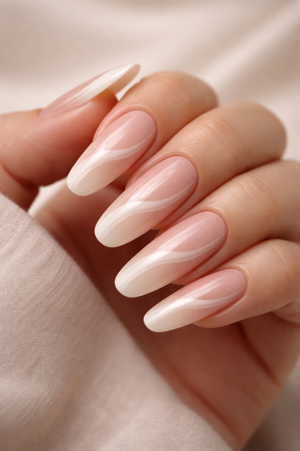 Close-up of long round acrylic nails with a wavy nude gradient following the curve