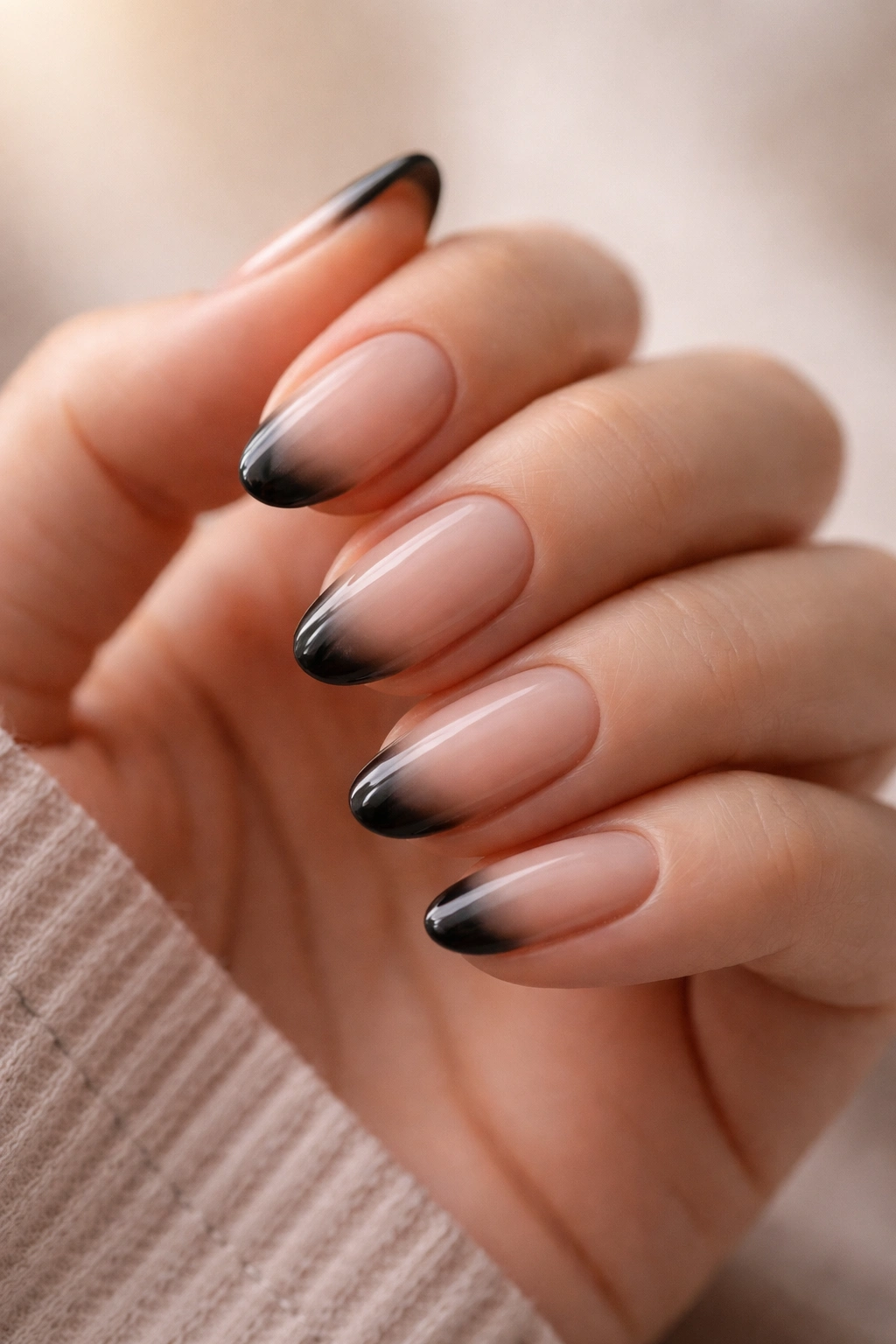 Close-up of short oval nails with nude-to-black gradient tips