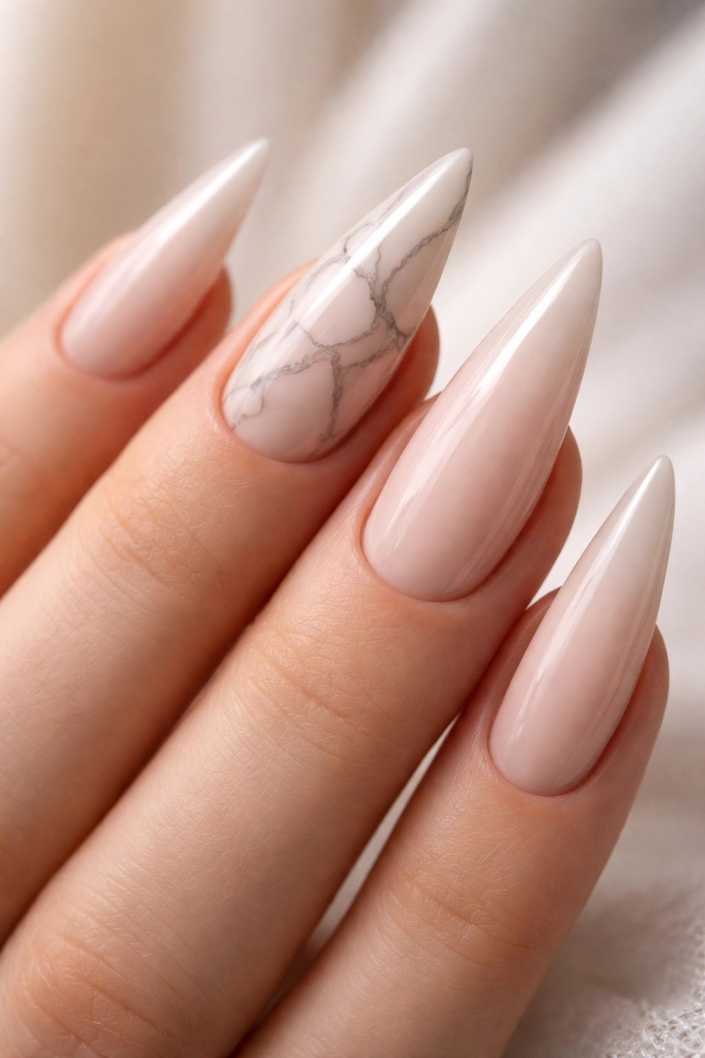 Close-up of nude nails with subtle gray marble veining on stiletto nails