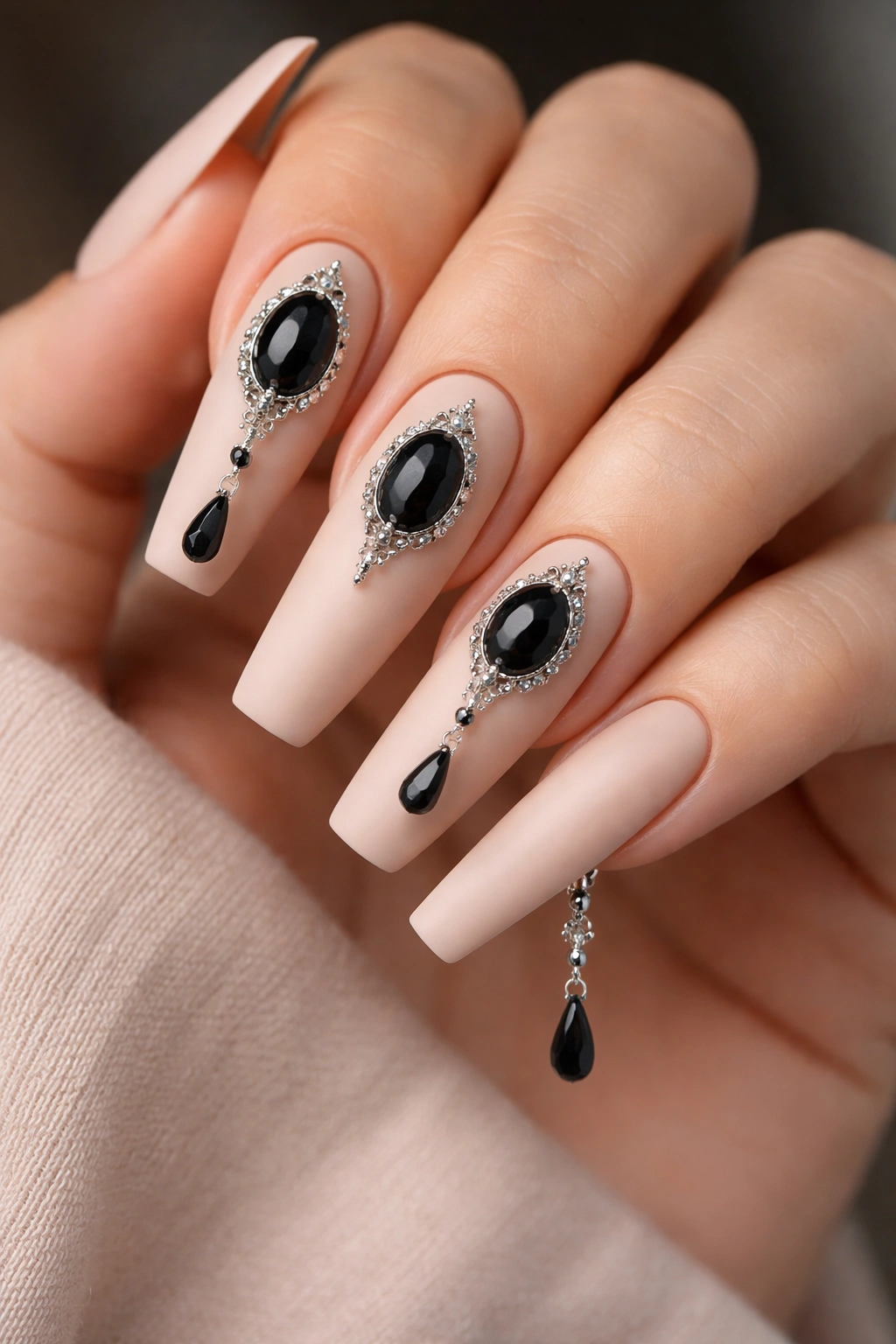 Matte nude nails with black onyx stone charms on several nails