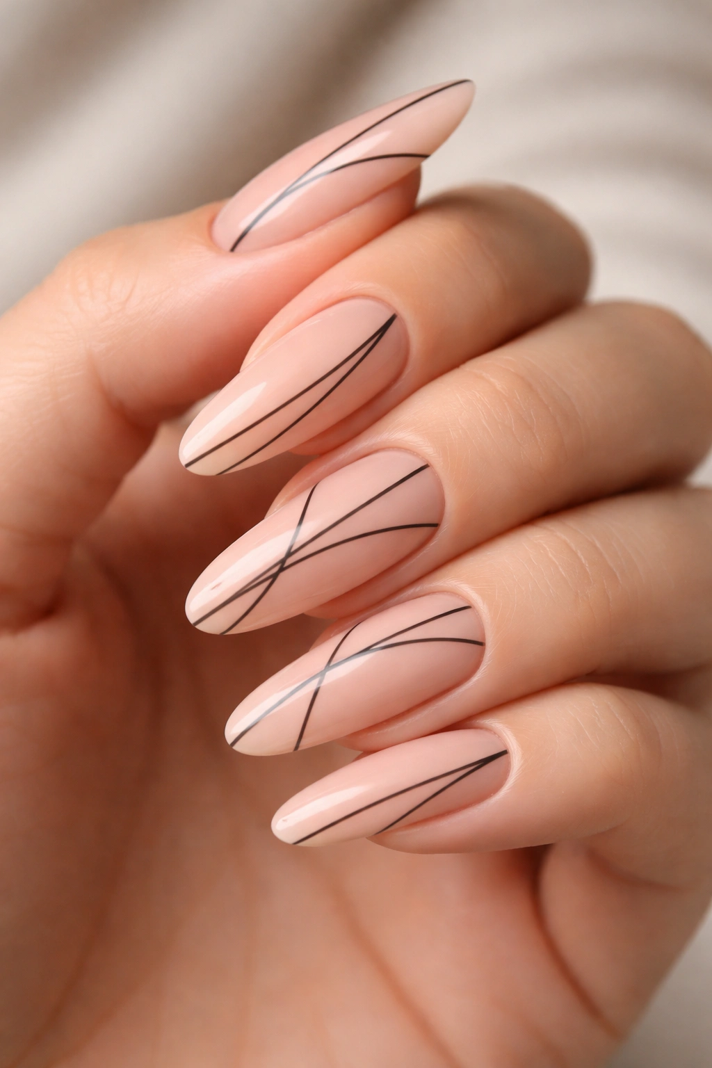 Close-up of long round acrylic nails with nude base and thin black lines