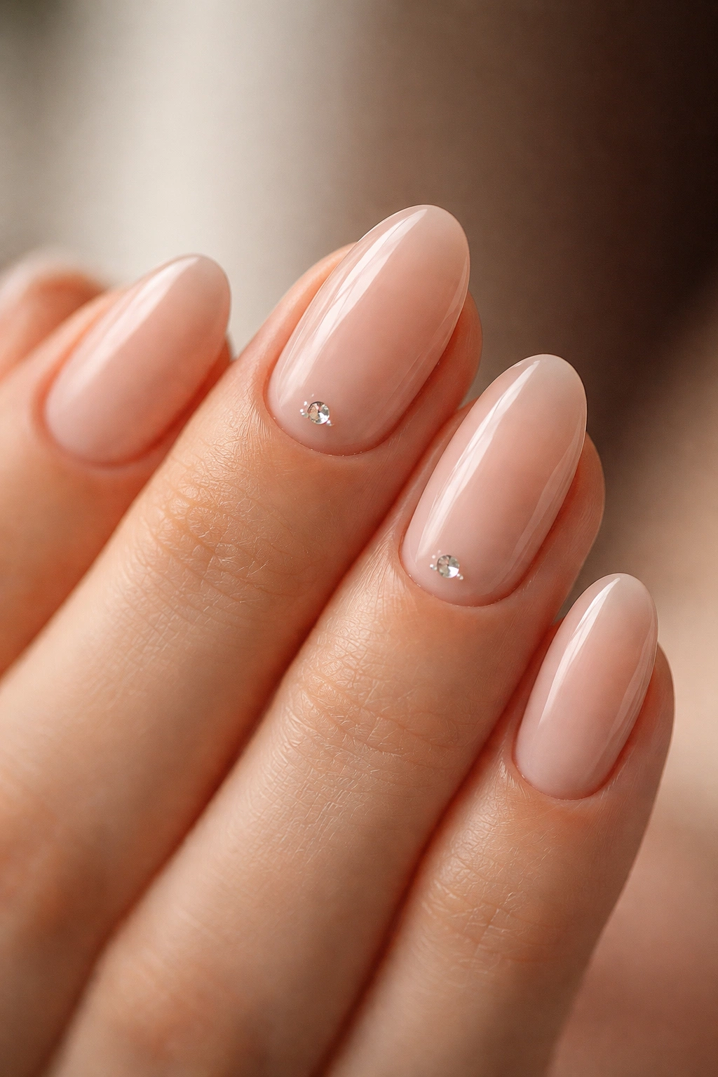 Nude almond nails with a single tiny crystal near cuticle on one or two nails