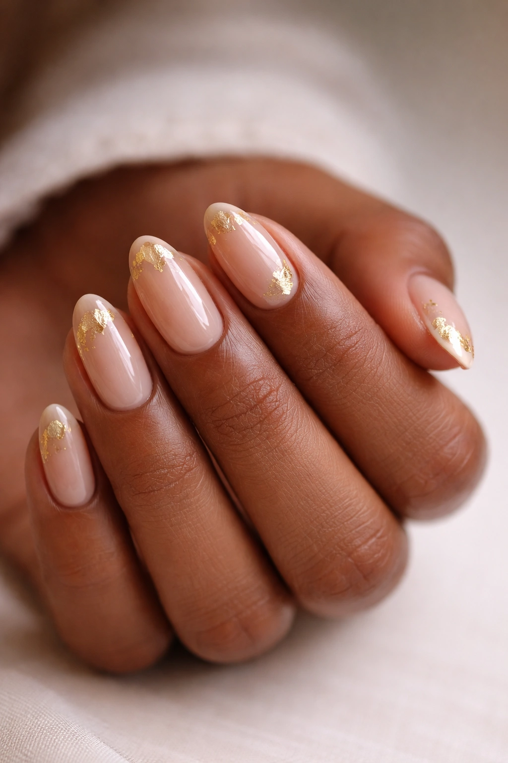 Close-up of nude nails with gold foil on short almond nails
