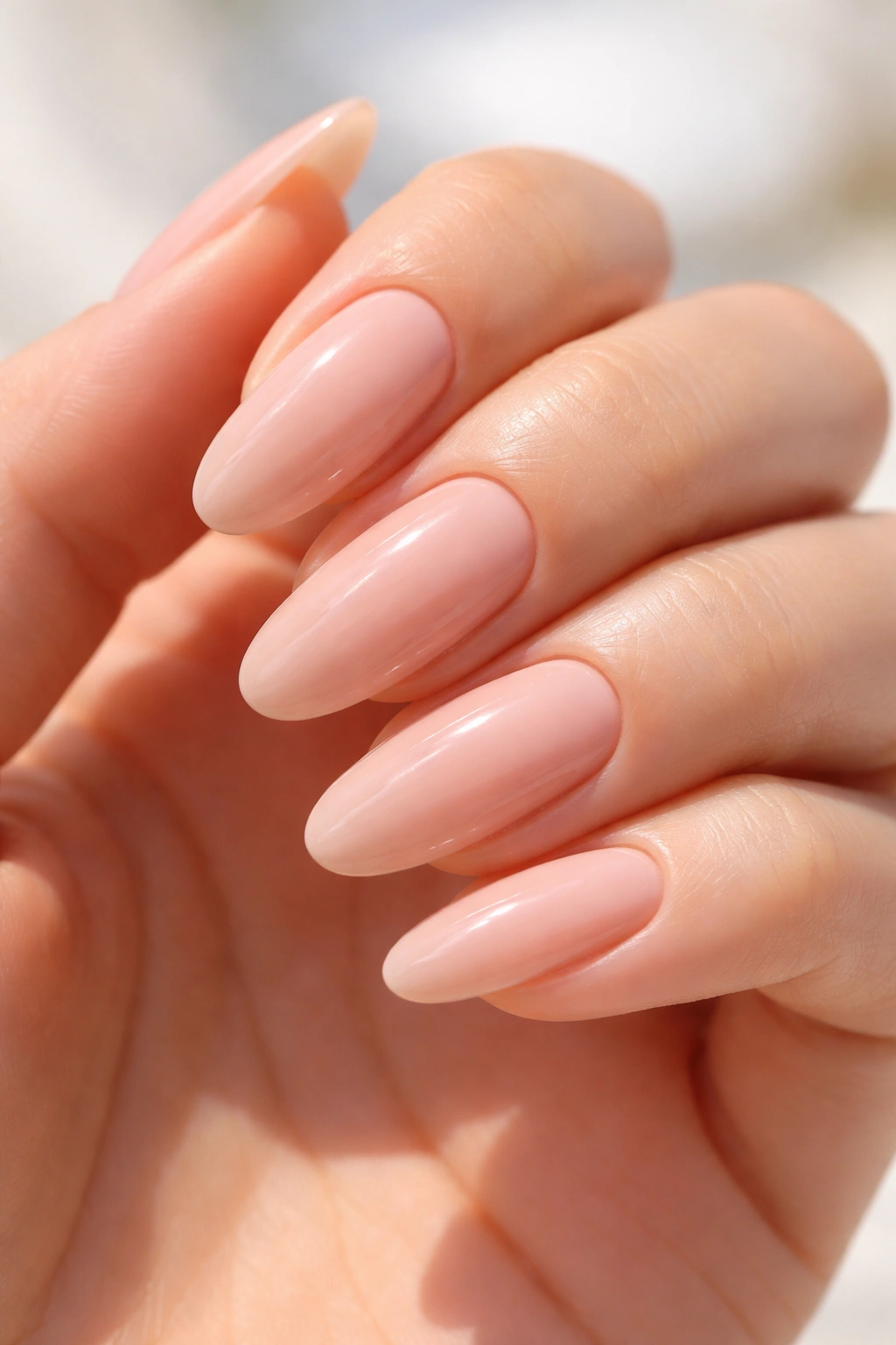 Close-up of nude nails with glossy topcoat on long rounded nails