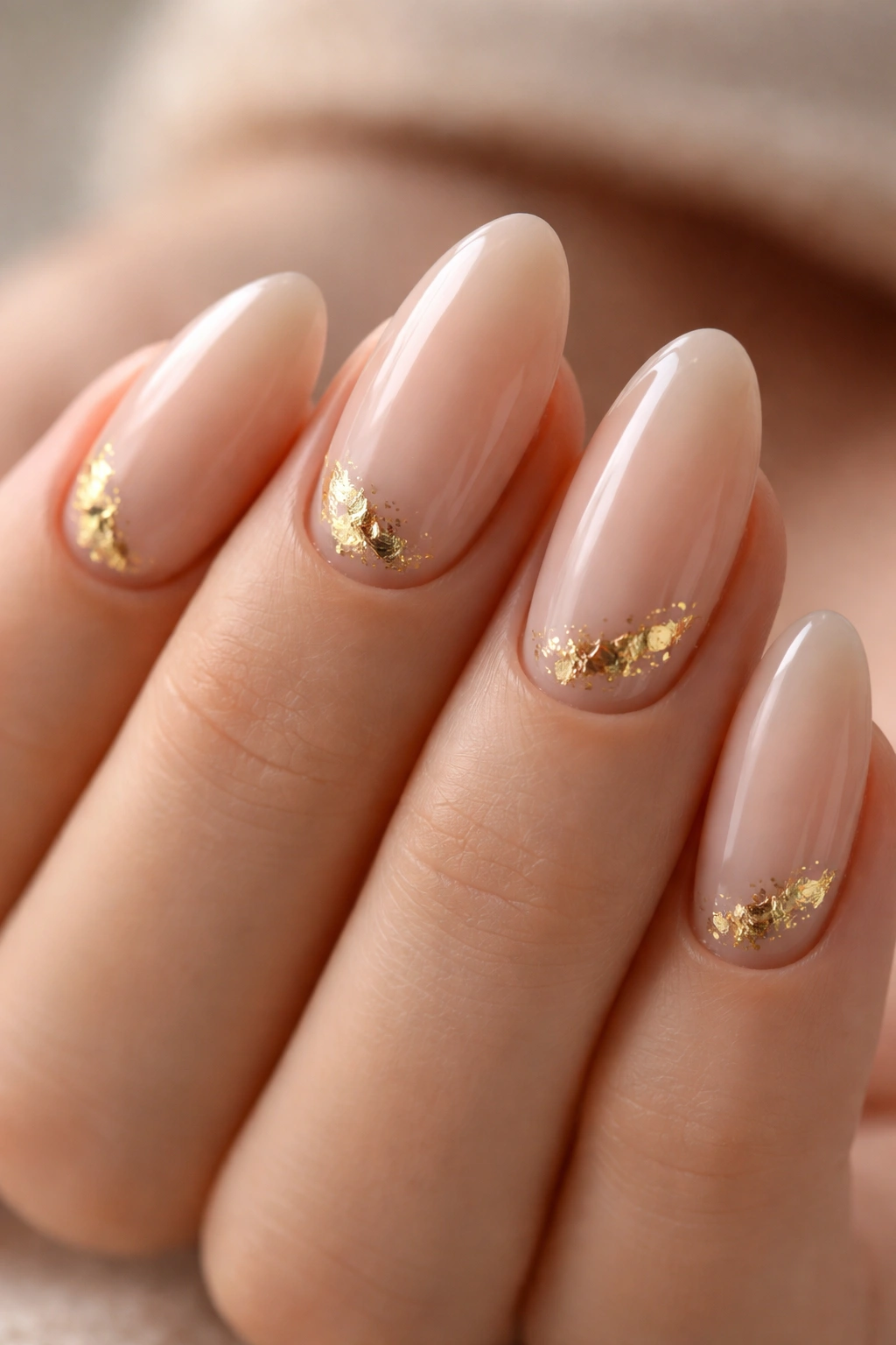 Nude almond nails with tiny gold foil accents