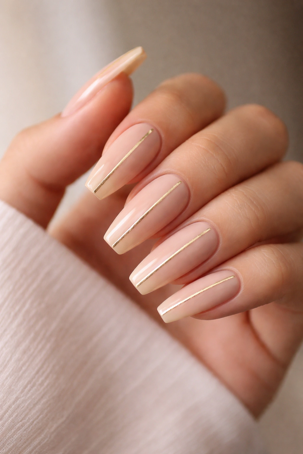 Close-up of nude nails with a central gold foil line