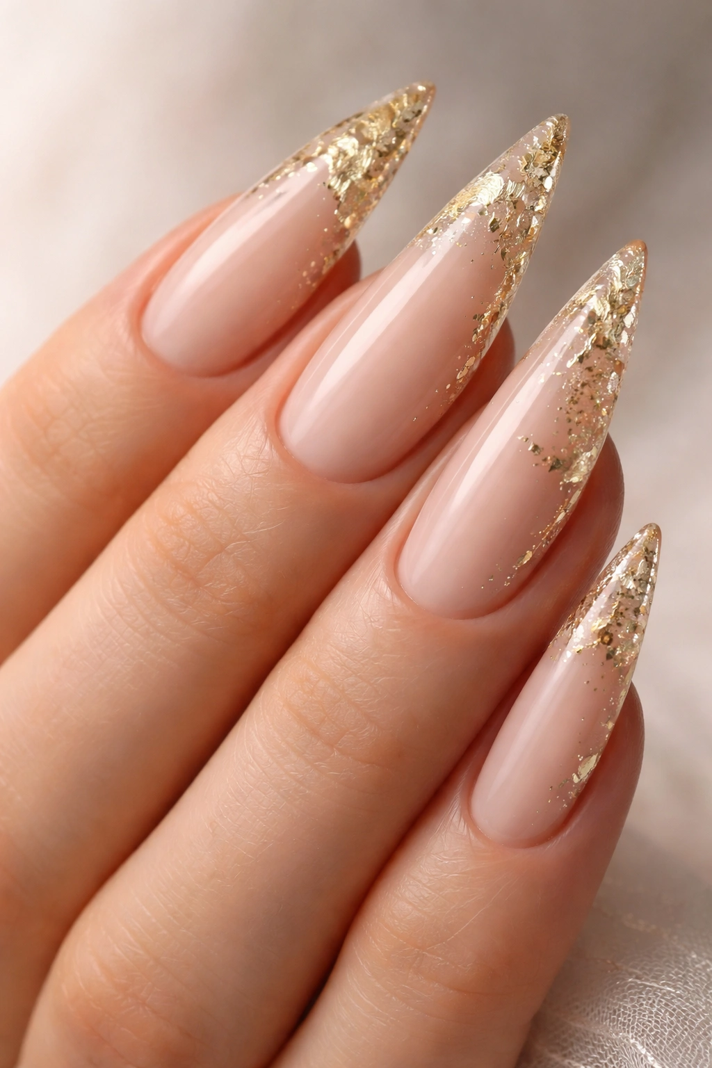 Nude stiletto nails with delicate gold leaf accents